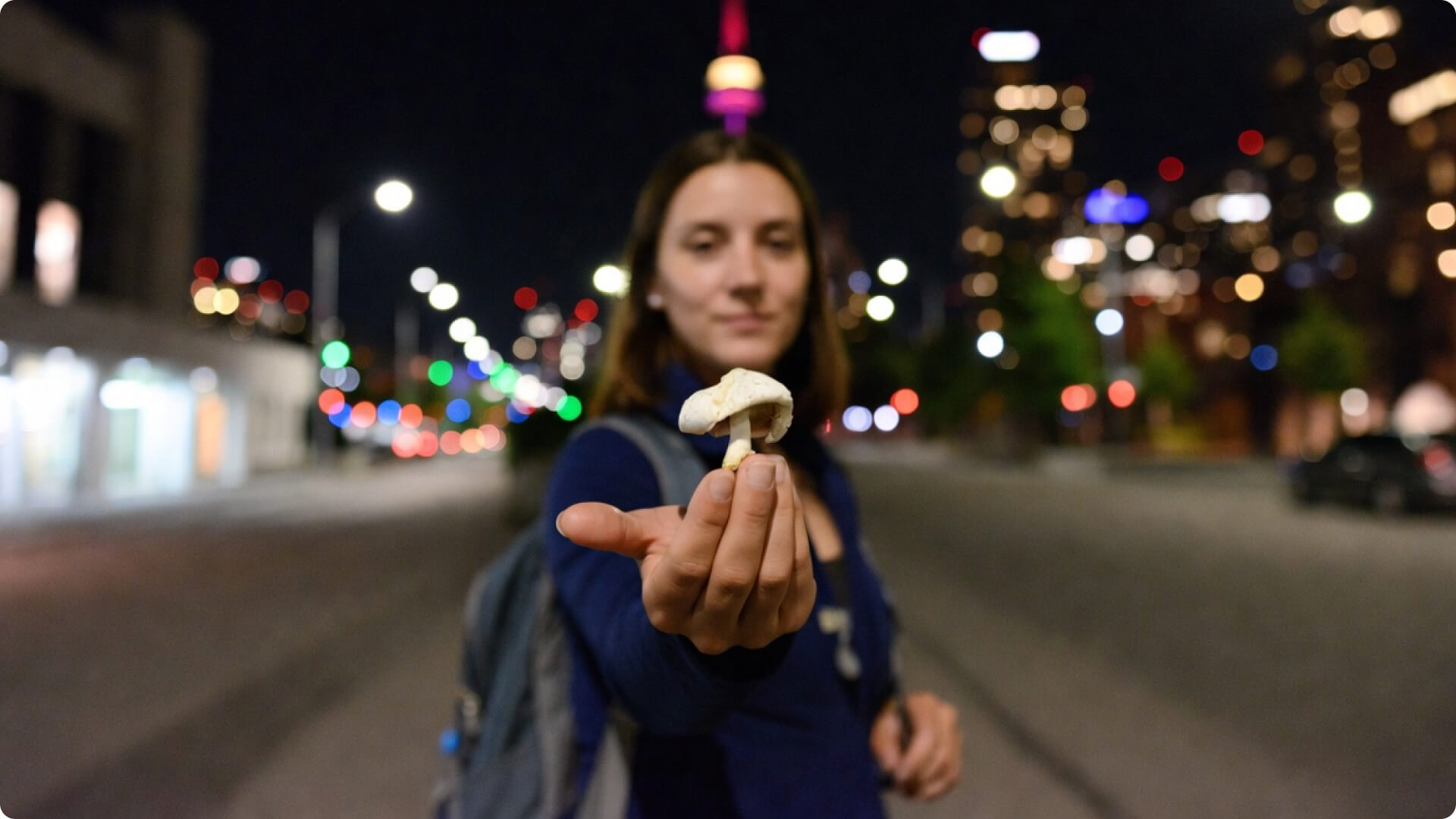 Young woman tourist holding a magic mushroom with Toronto in the background